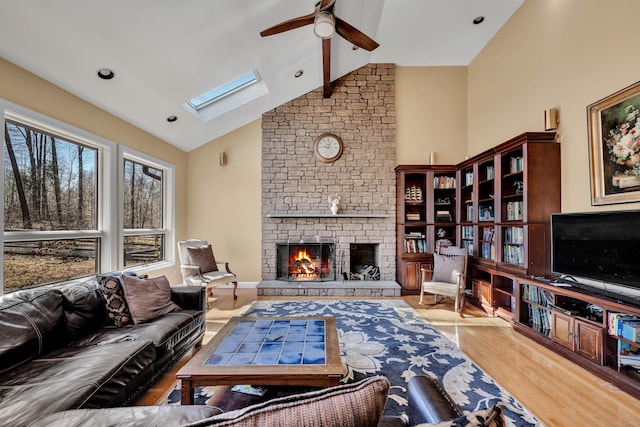 living area with a brick fireplace, ceiling fan, beam ceiling, wood finished floors, and high vaulted ceiling