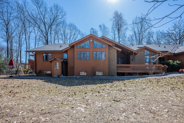 rear view of property with a deck and roof with shingles