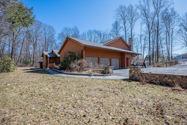 view of property exterior with a garage, a chimney, and a yard