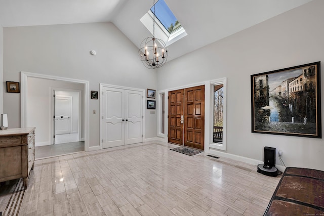 foyer featuring a skylight, baseboards, high vaulted ceiling, and wood finished floors