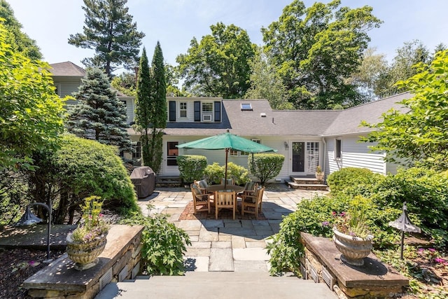 back of house featuring entry steps, a shingled roof, and a patio