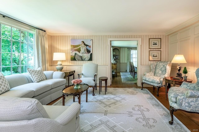 living area featuring light wood finished floors, ornamental molding, and a decorative wall