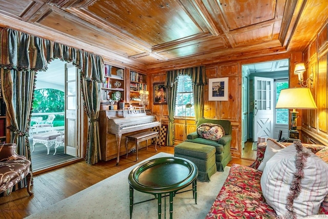 living area featuring crown molding, wood ceiling, wooden walls, wood finished floors, and coffered ceiling