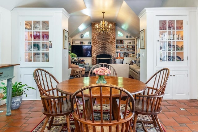 dining room with lofted ceiling, a fireplace, and a chandelier