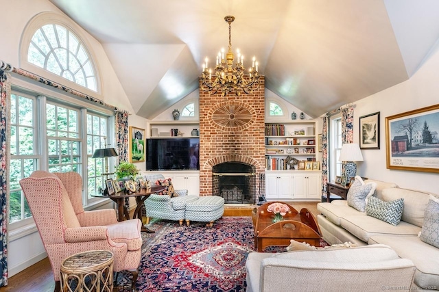 living area with built in shelves, a notable chandelier, a fireplace, wood finished floors, and high vaulted ceiling