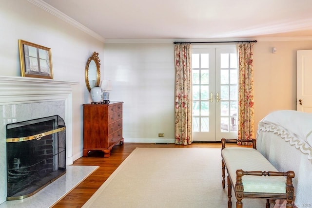 living area featuring crown molding, a premium fireplace, wood finished floors, and french doors