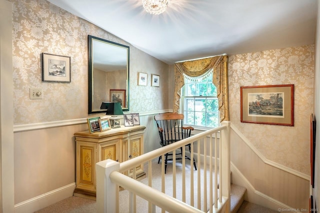 hallway with a wainscoted wall, an upstairs landing, and wallpapered walls