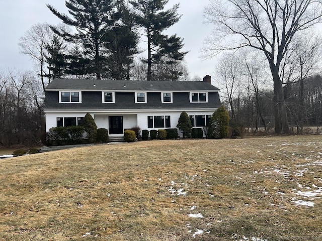 dutch colonial featuring a gambrel roof, a chimney, and a front lawn