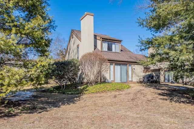 rear view of property featuring roof with shingles and a chimney