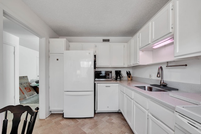 kitchen featuring white appliances, visible vents, white cabinets, light countertops, and a sink