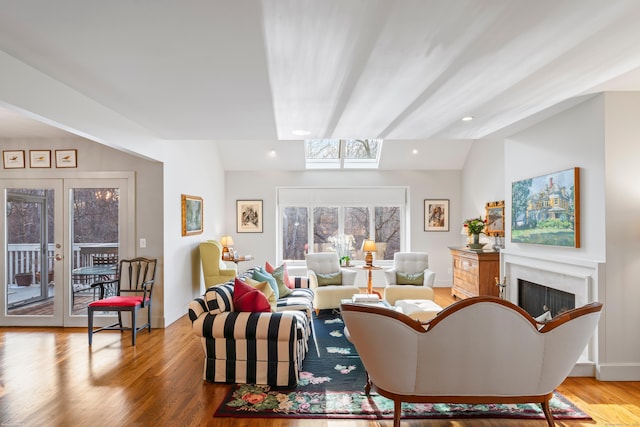 living room with wood finished floors, baseboards, lofted ceiling, a fireplace, and french doors