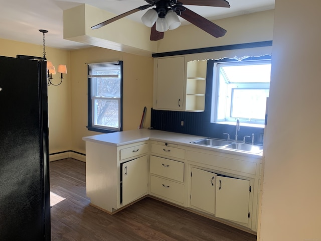 kitchen featuring a peninsula, dark wood-type flooring, a sink, light countertops, and freestanding refrigerator