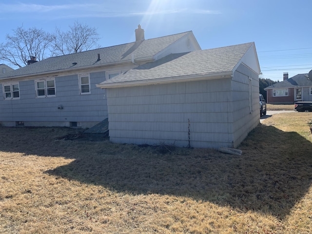 back of house with a shingled roof, a yard, and a chimney