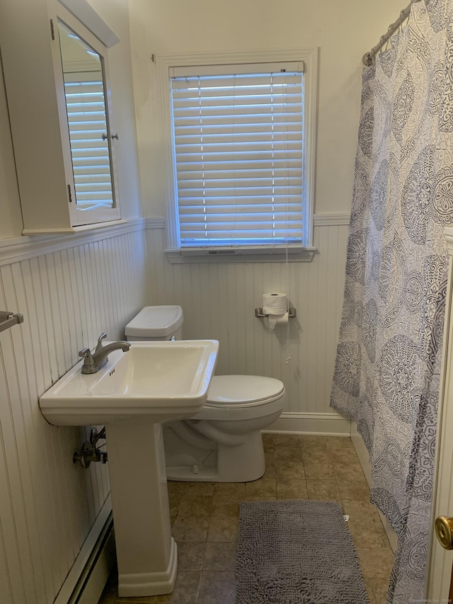 bathroom with a healthy amount of sunlight, wainscoting, toilet, and tile patterned floors