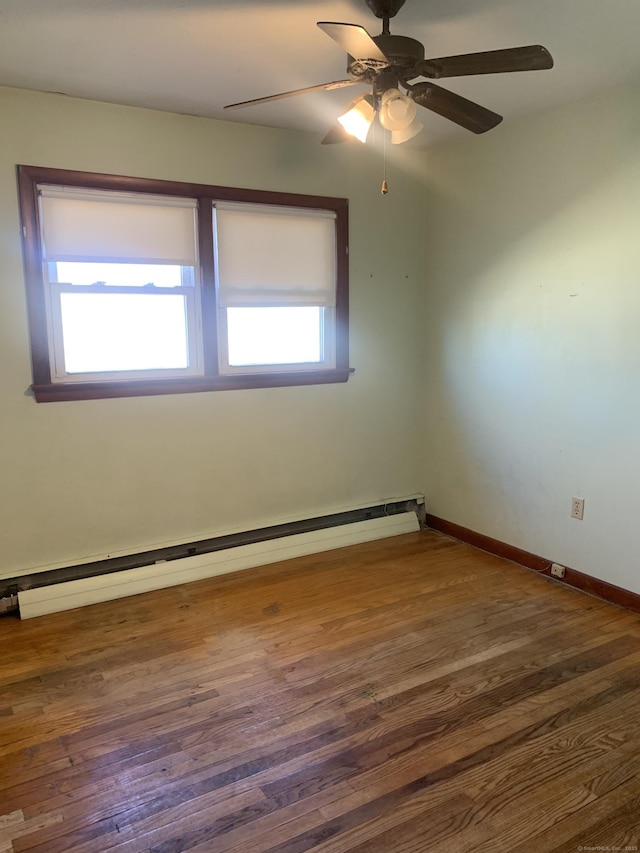 empty room featuring a ceiling fan, baseboards, a baseboard heating unit, and wood finished floors