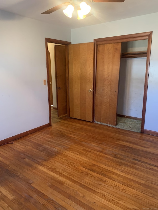 unfurnished bedroom featuring a ceiling fan, a closet, baseboards, and wood finished floors