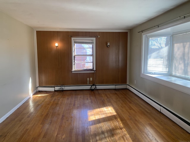 unfurnished room featuring baseboards, a baseboard heating unit, and hardwood / wood-style floors