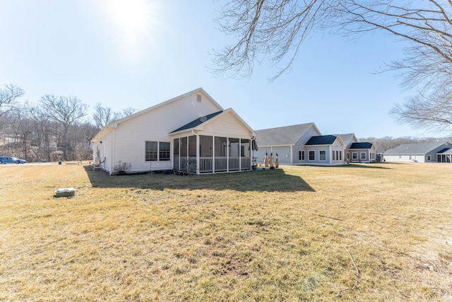 rear view of property with a sunroom and a yard