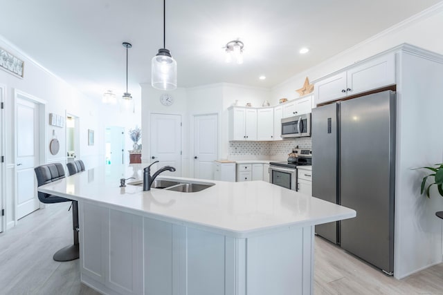 kitchen featuring tasteful backsplash, light wood-style flooring, appliances with stainless steel finishes, a sink, and a kitchen bar