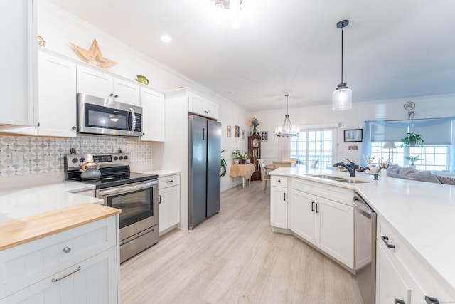 kitchen with appliances with stainless steel finishes, light countertops, a sink, and white cabinetry