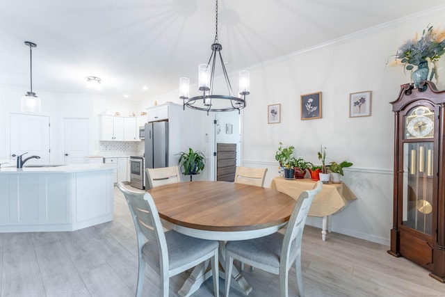 dining space with ornamental molding, a notable chandelier, light wood-style floors, and baseboards