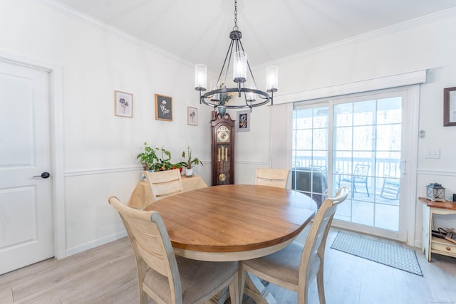 dining room with a chandelier, crown molding, light wood-style flooring, and baseboards