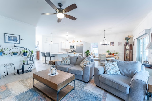 living area with a healthy amount of sunlight, light wood-style floors, crown molding, and ceiling fan with notable chandelier