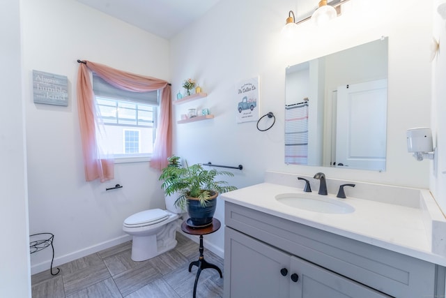 full bathroom featuring toilet, baseboards, and vanity