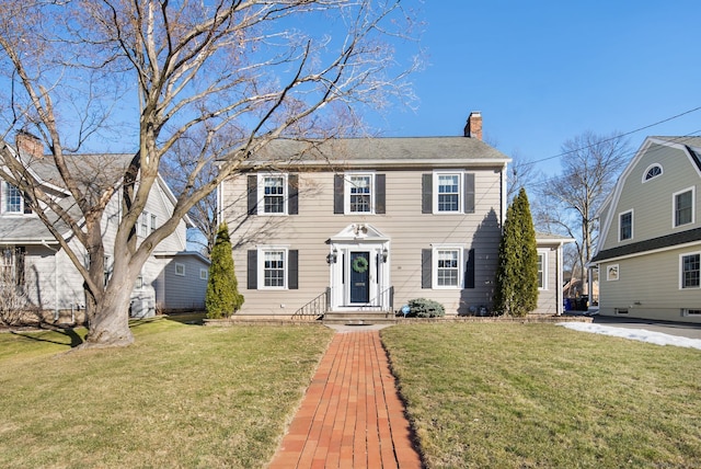 colonial house featuring a chimney and a front lawn