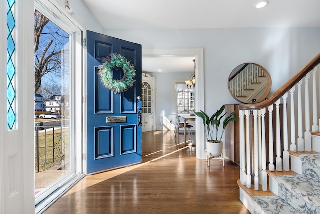 foyer entrance with recessed lighting, stairway, an inviting chandelier, and wood finished floors