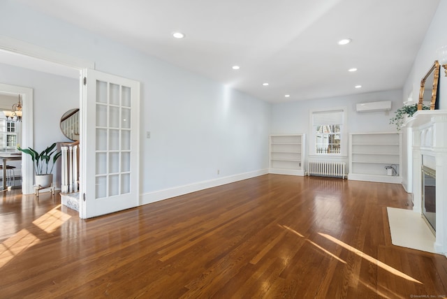 unfurnished living room with recessed lighting, radiator heating unit, a premium fireplace, an AC wall unit, and wood finished floors