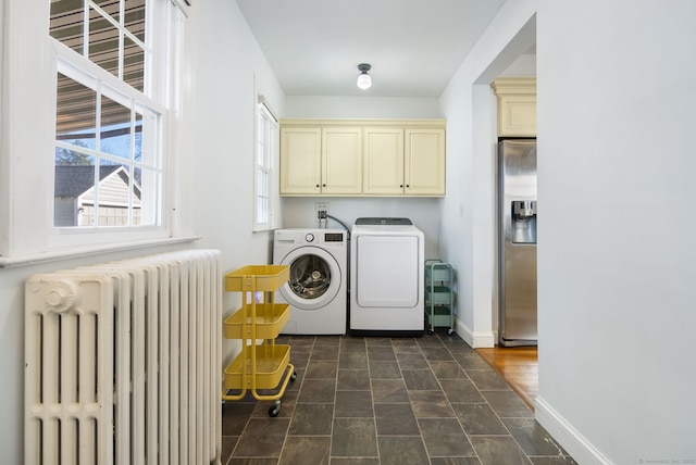 laundry area featuring baseboards, independent washer and dryer, cabinet space, and radiator