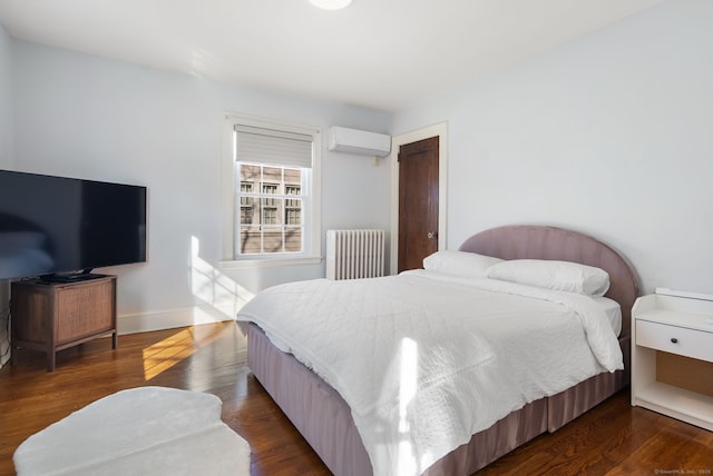 bedroom with radiator heating unit, baseboards, dark wood-type flooring, and a wall mounted air conditioner