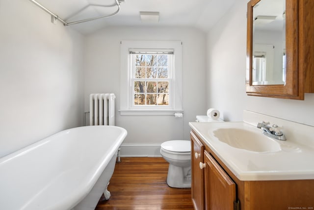 bathroom with radiator, a soaking tub, vaulted ceiling, and wood finished floors