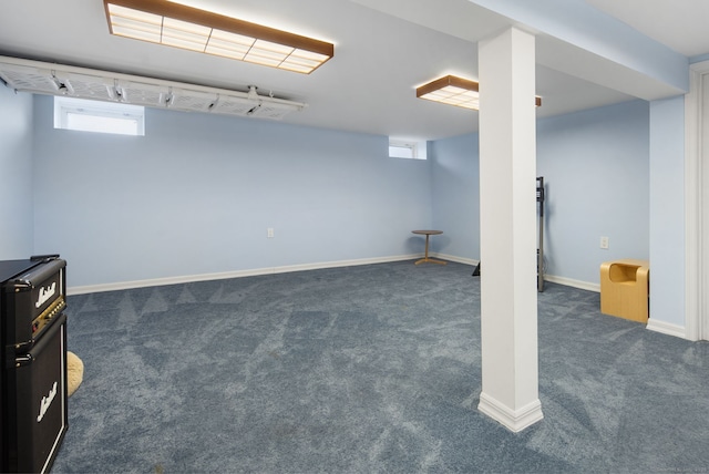 basement featuring plenty of natural light, dark carpet, and baseboards