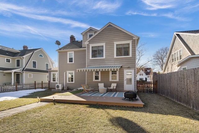 rear view of house with a deck, a fenced backyard, a fire pit, a yard, and a chimney