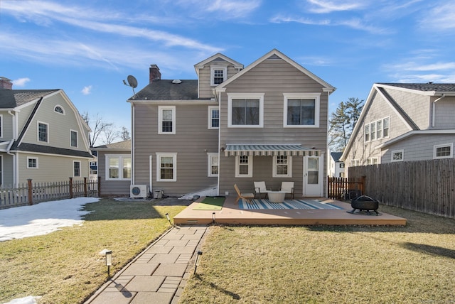 back of property with a fenced backyard, a fire pit, a lawn, a wooden deck, and a chimney