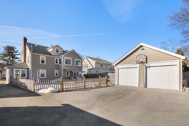 view of front of property with a garage, a fenced front yard, a residential view, and an outbuilding