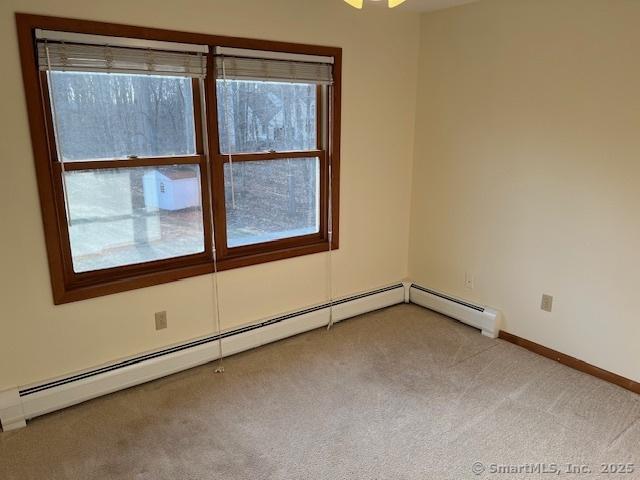 empty room with a baseboard radiator, baseboards, and carpet flooring