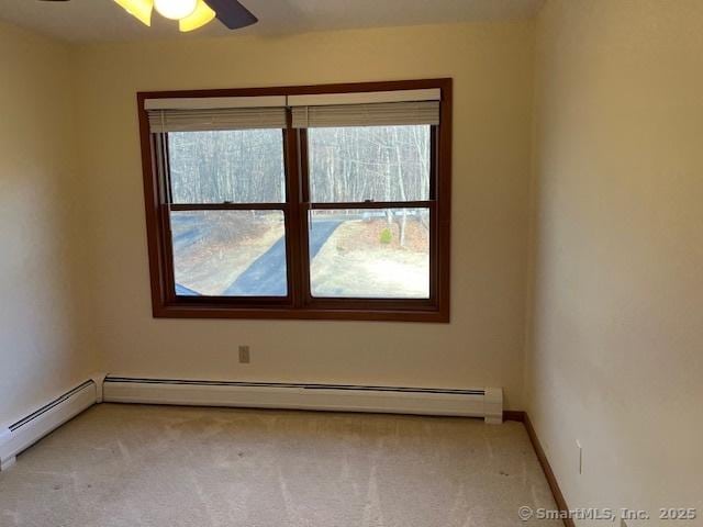 empty room featuring light colored carpet, baseboards, a ceiling fan, and a baseboard radiator