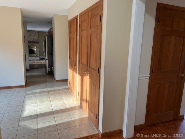 hall featuring light tile patterned flooring and baseboards