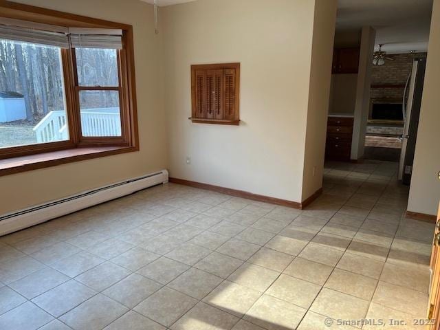 spare room featuring light tile patterned floors, a ceiling fan, baseboards, and a baseboard radiator