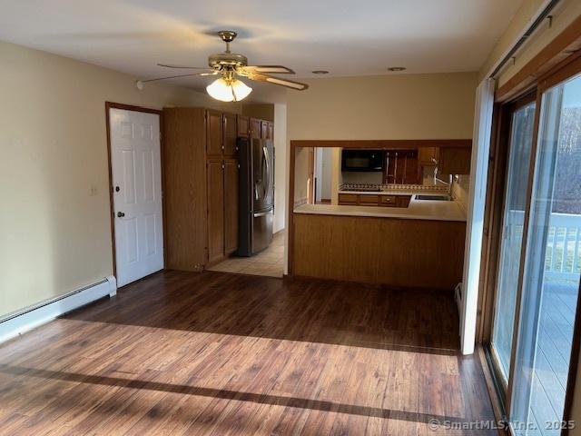 kitchen featuring a ceiling fan, a sink, wood finished floors, freestanding refrigerator, and black microwave