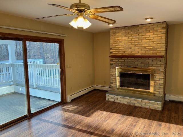 unfurnished living room featuring a baseboard heating unit, wood finished floors, a fireplace, baseboards, and ceiling fan