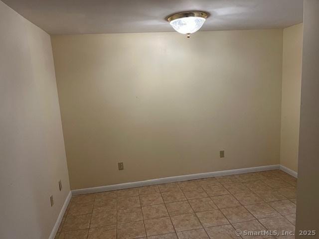 unfurnished room with light tile patterned floors and baseboards