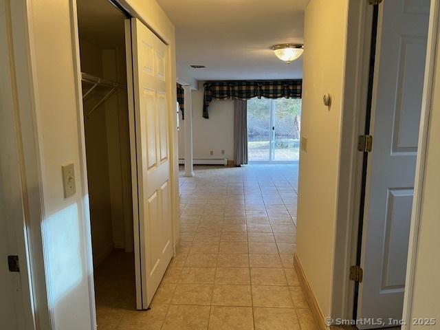 hall featuring light tile patterned flooring, baseboards, and a baseboard radiator