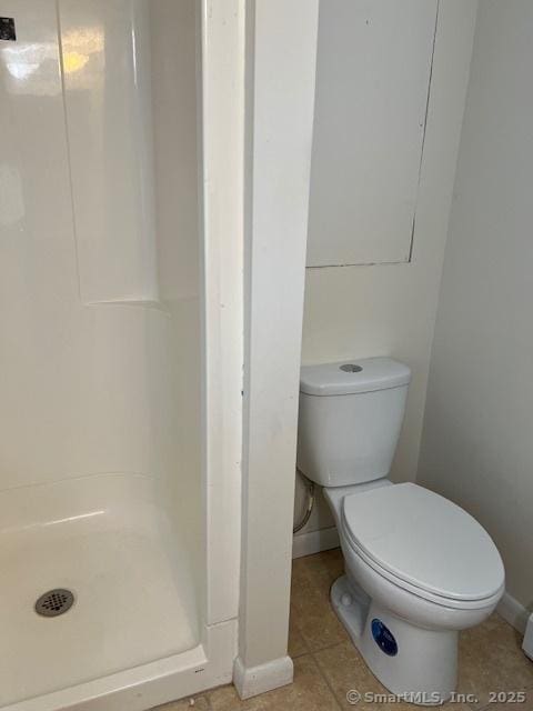 bathroom featuring baseboards, toilet, a shower stall, and tile patterned flooring