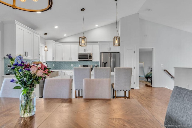 interior space featuring recessed lighting, high vaulted ceiling, and light wood-style floors