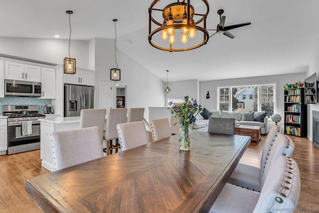 dining room featuring light wood finished floors, recessed lighting, high vaulted ceiling, and an inviting chandelier