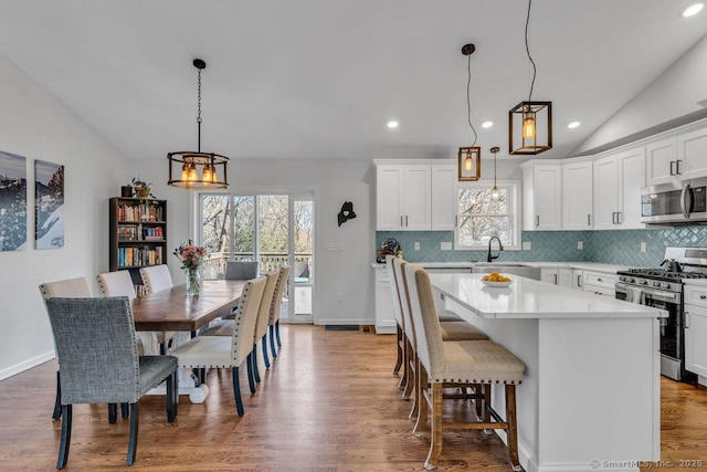 kitchen with backsplash, a kitchen island, vaulted ceiling, stainless steel appliances, and a sink